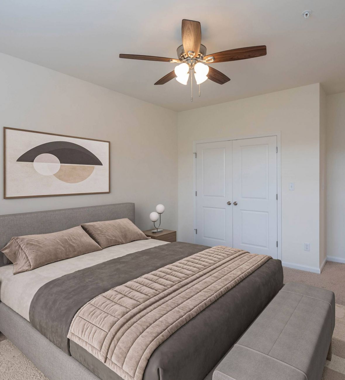 Modern bedroom with a gray bed, two nightstands, abstract art, and a ceiling fan with lights.